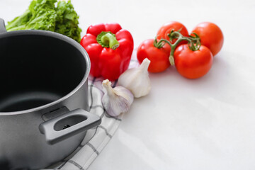 Cooking pot with vegetables on white table