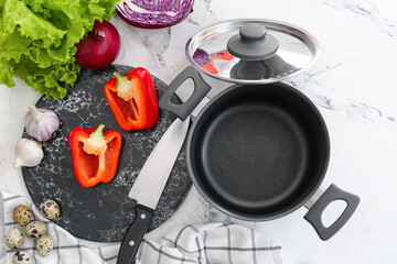 Cooking pot with vegetables on light background