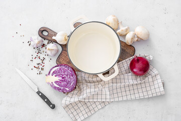 Composition with cooking pot and vegetables on light background