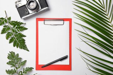 Clipboard with blank paper sheet and photo camera on white background