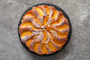 Board with tasty peach pie on grunge background