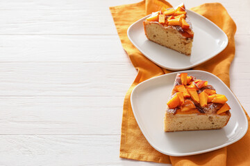 Plates with pieces of tasty peach pie on wooden background