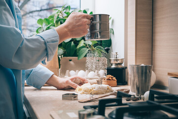 A girl without a face prepares dough, sprinkles it with flour, close-up. Cooking homemade cakes in the kitchen, at home. Culinary background
