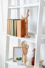 Shelf unit with books and decor near white wall in room