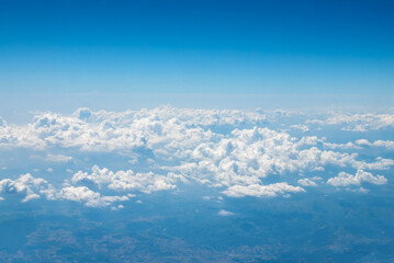 Blue sky with large beautiful clouds and a top view of the earth on a bright sunny day from the window of a flying plane. Sky replacement template