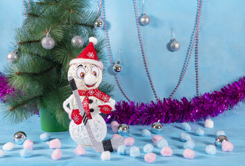 A cheerful but lonely snowman in a red outfit with a hockey stick stands next to a green tree on a blue new year stage