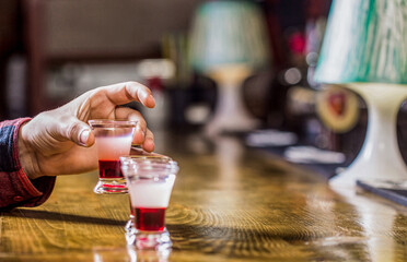 Drinking alcohol into shot glasses in a nightclub or bar. Man shots cocktail. Tequila shots, vodka,whisky, rum. Barman in pub. Tequila shot. Colorful cocktails at the bar