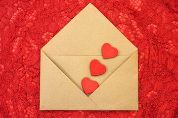 On a red openwork background an open envelope with three red hearts. Festive background