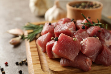 Board with raw meat, herbs and spices on gray background