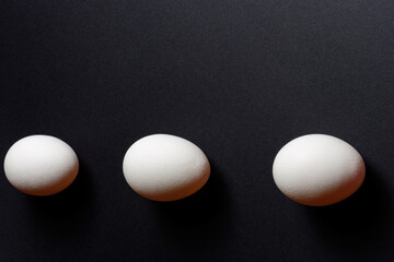 Three white eggs on a black background, dietary and healthy food rich in protein.