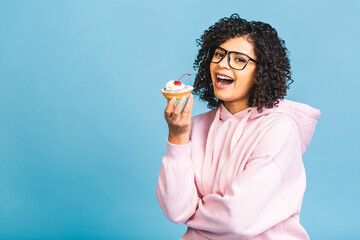 Black american african happy woman with curly afro hair style making a mess eating a huge fancy...