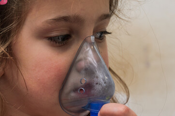 Little girl child makes inhalation with mask on face	
