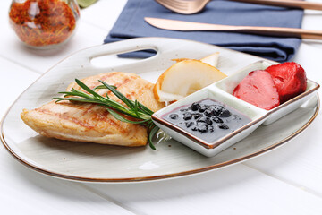 Grilled chicken breast with berry sauce in plate on white wooden table