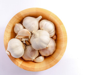 Garlic in a wooden bowl on a white background
