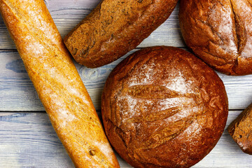 An assortment of fresh crispy breads. View from above. Bread counter at the bakery. Rye bread, baguette on a light wooden table.