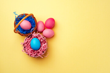 Decorative nest with colorful Easter eggs on yellow background