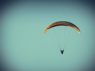 Paraglider flying in blue sky.