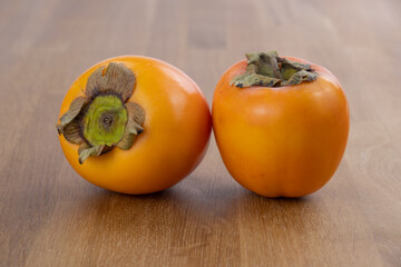 Zwei reife exotische Kaki Früchte auf einem hölzernen Hintergrund