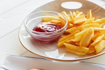 French fries potatoes in plate with sauce on wooden table