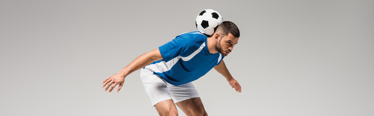 Young sportsman holding football on back isolated on grey, banner