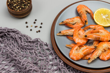 Shrimp in gray bowl. Gray mesh, rosemary branch, allspice and lemon on table