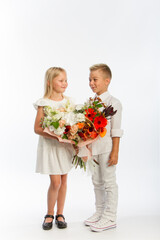 Studio portrait boy gives girl festive bouquet, congratulatory concept, white background, copy space
