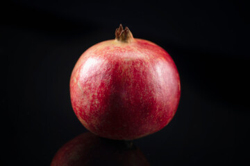 Fototapeta na wymiar Pomegranate on a Black Reflective Background