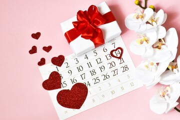 Valentine's day card. Calendar, gift box, orchid flower and red hearts on a pink background. concept of holidays Valentine's Day, Mother's Day, Birthday.
