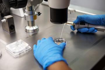 Hands of a scientist in the laboratory with a test tube and a microscope. The invention of the...