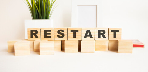 Wooden cubes with letters on a white table. The word is RESTART. White background.