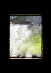 Small window in a dark room (or cellar) with broken glass and fresh bright outside view 