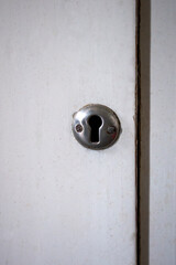 White old dirty scratched cupboard door with small silver round keyhole (with two small screws)