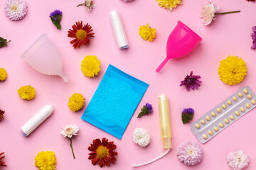 Menstrual cup, oral contraceptives and medical tampons with flowers top view