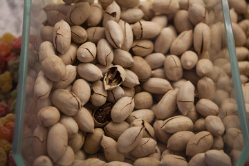 Peking nuts in their shells in a plastic transparent container on the counter of a store.
