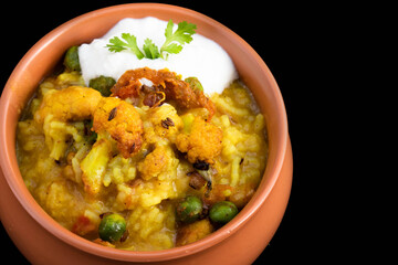 Delicious Daal Khichadi Also Known As Daliya Khichuri Or Dal Khichdi Sauteed With Indian Spices And Vegetables Served With Curd In Clay Pot Handi On Black Background With Copy Space For Custom Text