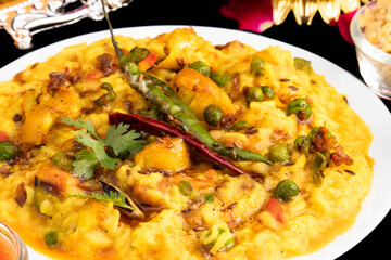 Indian Food Daal Khichadi Also Known As Daliya Khichuri Or Masala Dal Khichdi Loaded With Startled Desi Ghee Spices And Assorted Vegetables. Isolated On Black Background With Blank Copy Space For Text