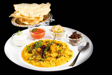 Popular Daal Khichadi Also Known As Daliya Khichuri Or Dal Khichdi Sauteed With Indian Spices Tadka Served With Dahi Chatni Tomato Chutney Aloo Bharta Achar Pickles Crispy Papad. Black Background