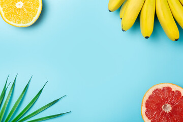 Tropical fruits summer background. Bananas, oranges and grapefruits on a colored blue background. Smoothie, summer vacation, travel and vitamins concept.