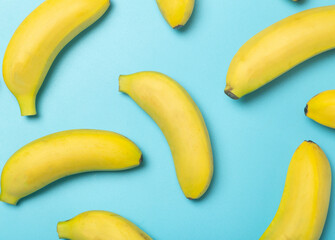 Bananas on a colored background. Pattern of yellow fresh bananas on a pure blue background. Minimal and creative concept.