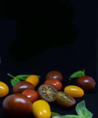 Multi-colored cherry tomatoes on a dark background with space for text. Banner, poster, layout.