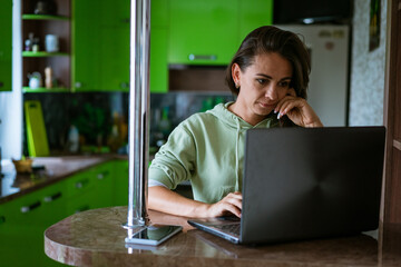 Young woman in kitchen with laptop