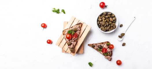 Appetizer bruschetta with tuna. Italian bruschetta sandwiches with canned tuna, tomatoes and capers. toasts with tuna delicious healthy food on a dark background, Top view, flat lay