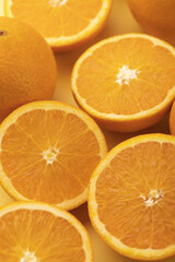A vertical shot of slices of fresh orange on a yellow surface