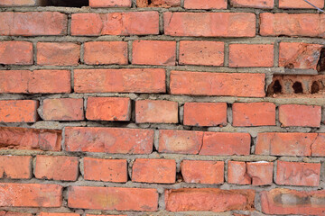 Fragment of an old brick wall with cracked joints and crumbling bricks