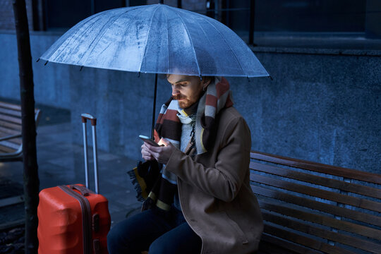 Man Sitting At The Bench Under The Transparent Umbrella