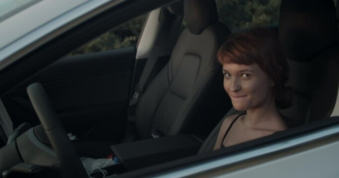 Cut girl in an electric car looking through window. Handheld video