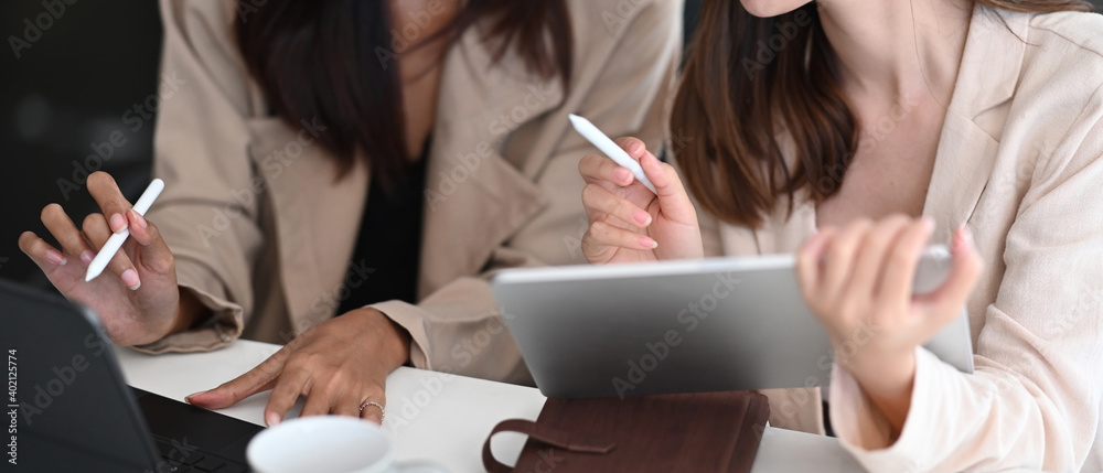 Wall mural cropped shot of two businesswoman explaining presentation on digital tablet at co working area.