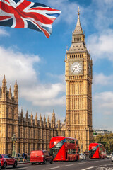 Fototapeta na wymiar Big Ben with red buses on the bridge against flag of England in London, England, UK