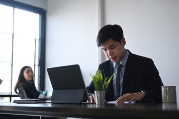Fototapeta premium Businessman using tablet computer and concentrate analyzing business documents while sitting with his colleague in office.
