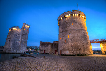 Fototapeta na wymiar ancienne tour de fortification de l'entré du port dans le centre historique de la Rochelle en France au couché du soleil